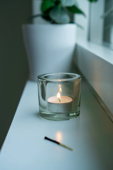 Mała świeczka tealight Aura pf10-50s w szklanym świeczniku na parapecie