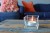 Świeczka tealight Aura pf10-50s zapalona w szkle na stoliku