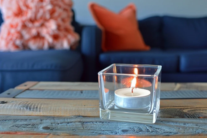 Świeczka tealight Aura pf10-50s zapalona w szkle na stoliku